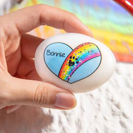 Person holding a personalized pet memorial rock with rainbow bridge design and the name Bonnie engraved