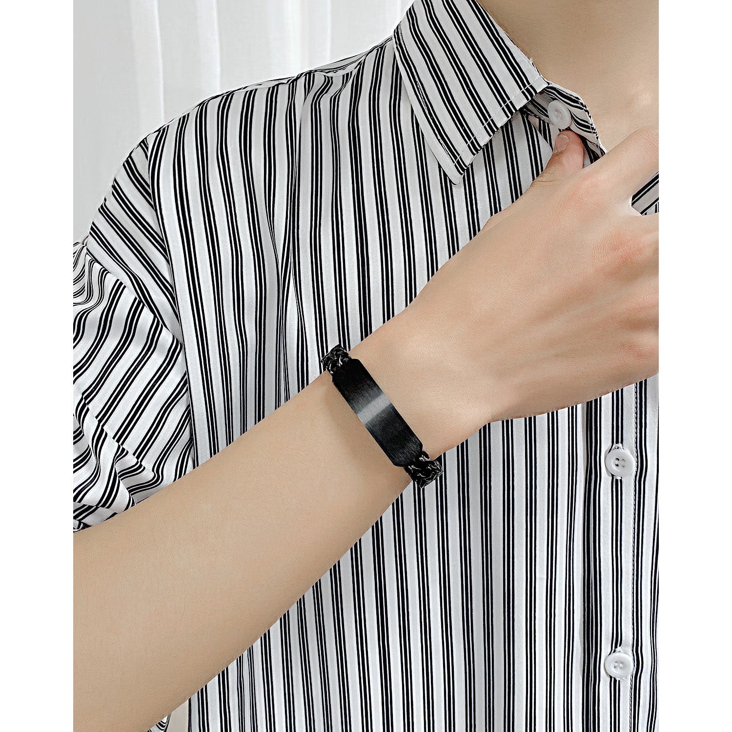 A close-up of a person wearing a custom men's name bracelet available in black 