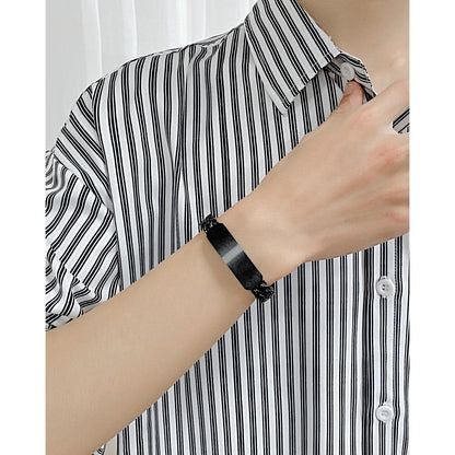A close-up of a person wearing a custom men's name bracelet available in black 
