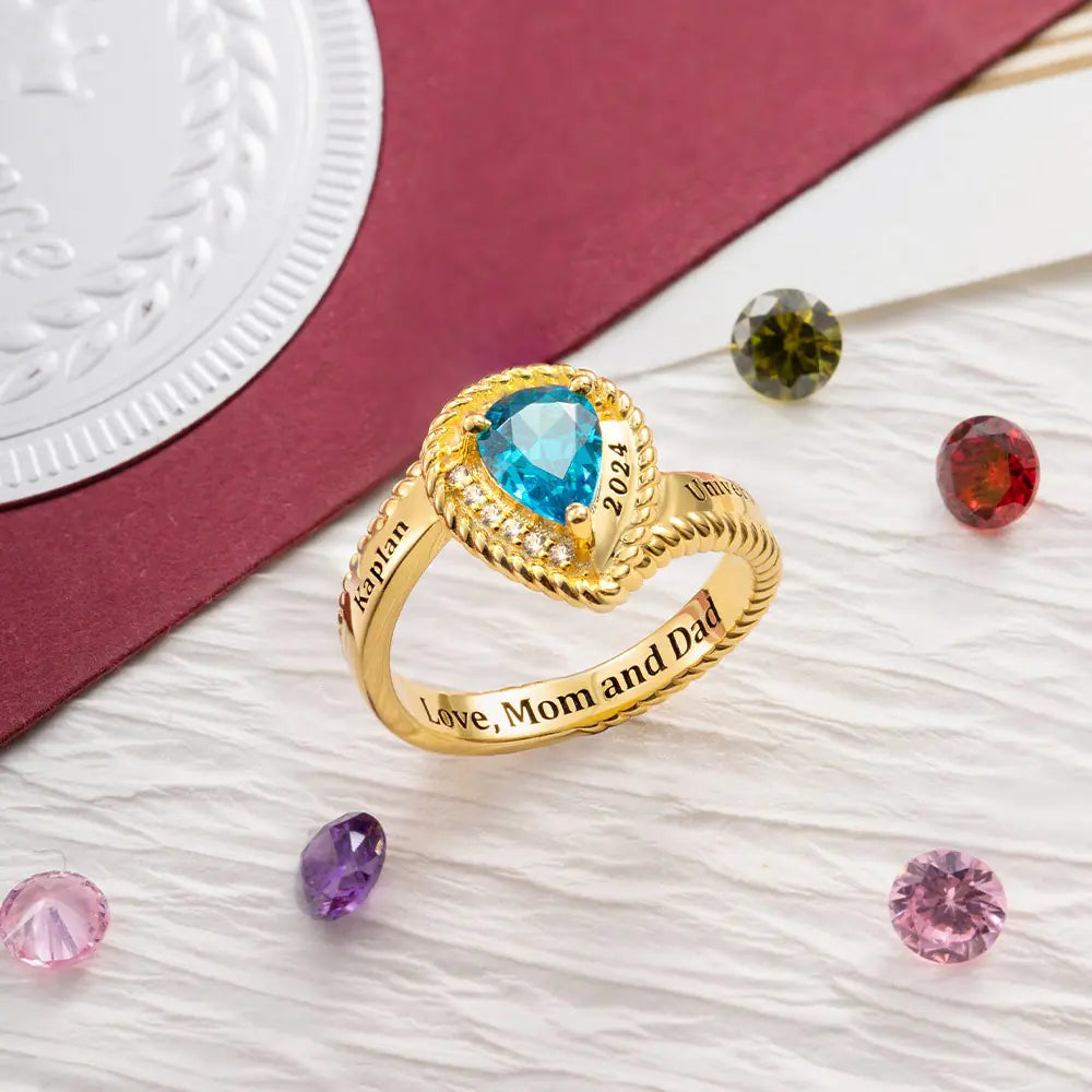 Custom gold class ring with blue birthstone and engraved message “Love, Mom and Dad