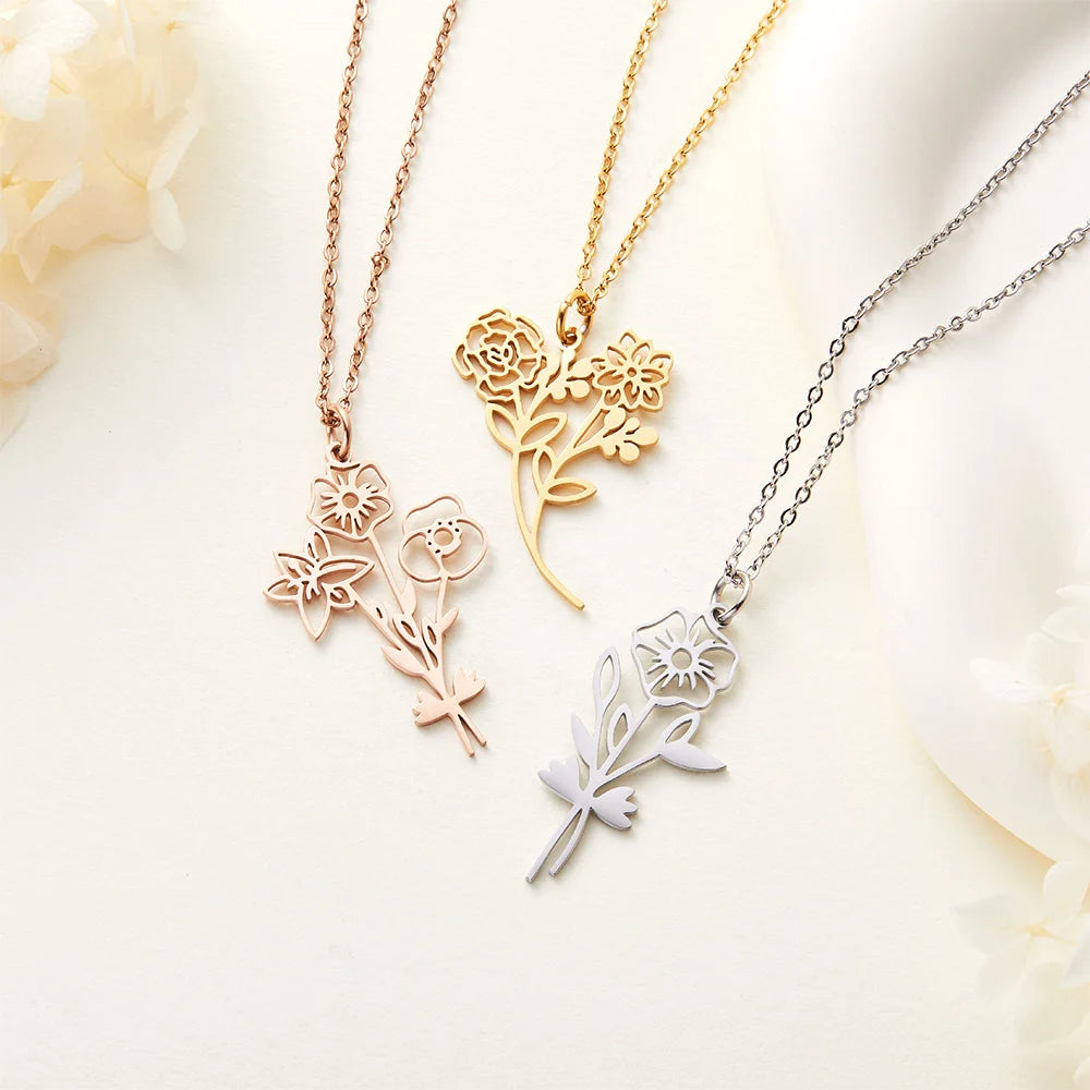 Three floral necklaces in rose gold, gold, and silver on a soft white background.