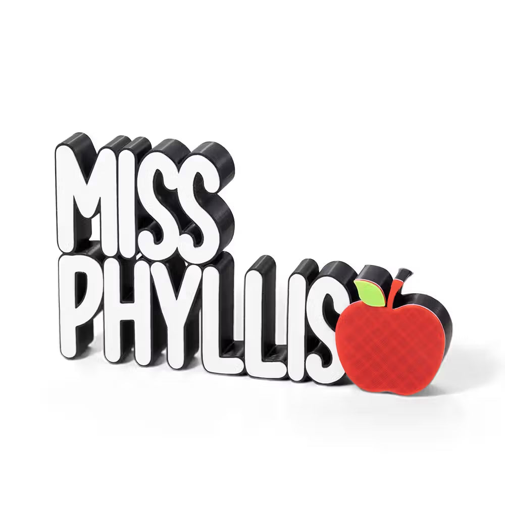 A custom 3D block-style sign reading 'MISS PHYLLIS' in white letters with black sides, plus a red apple with a green leaf on the right, shown on a clean white background.