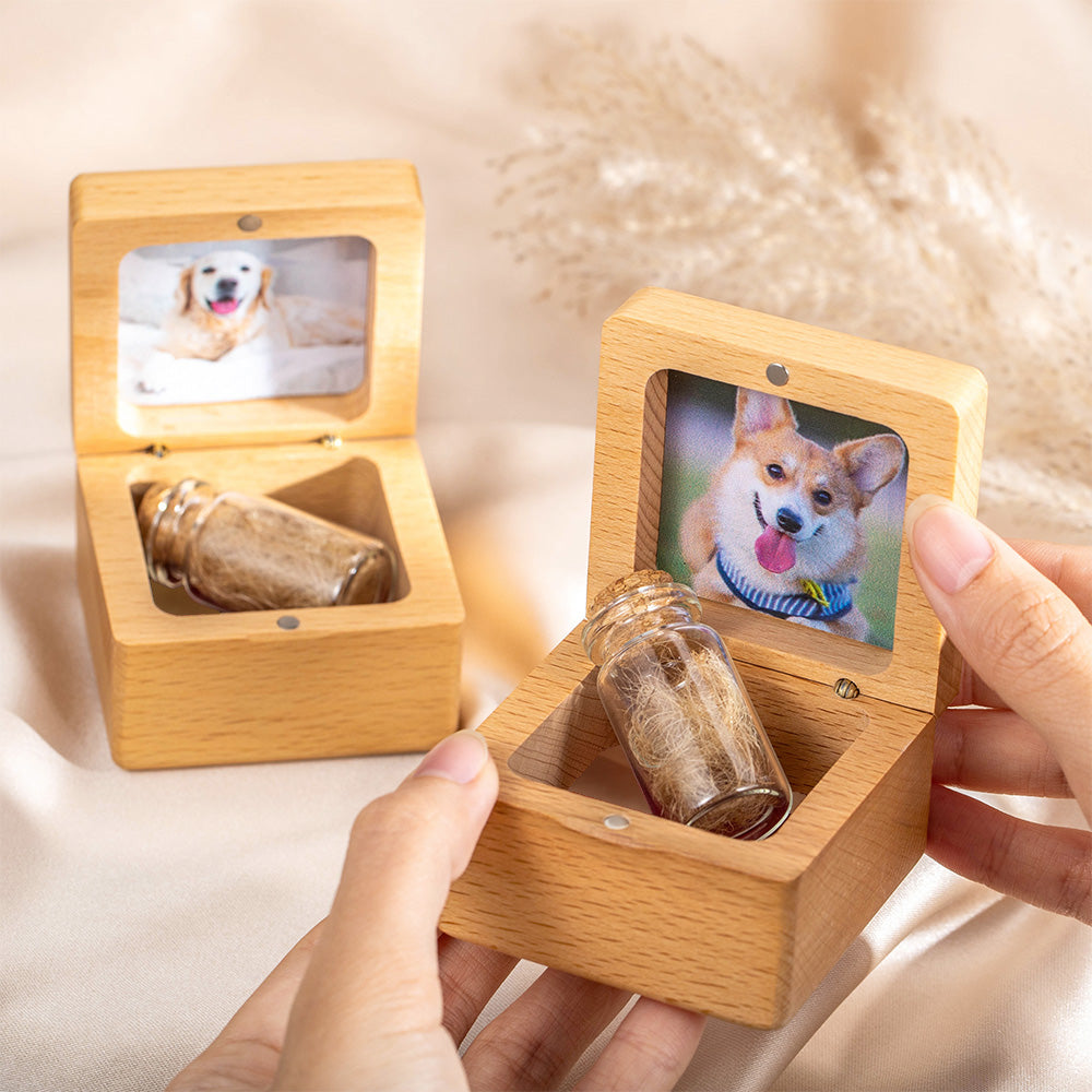 Wooden box with a small glass jar containing pet cremation ashes, with a photo of a dog on the lid.