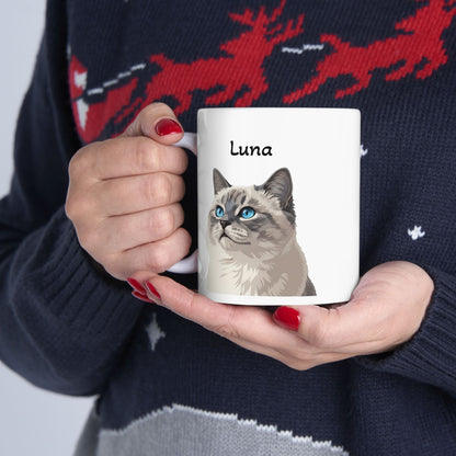 Person holding a mug with a cat illustration and 'Luna' text, wearing a sweater with reindeer design.