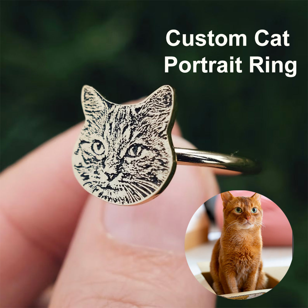 A custom cat portrait ring held between fingers, with an inset image of a real cat.