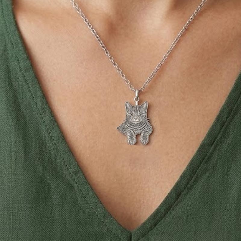A custom silver cat pendant necklace on a person wearing a green top