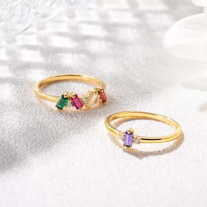 Two custom baguette birthstone rings in gold, showing different personalized stone combinations