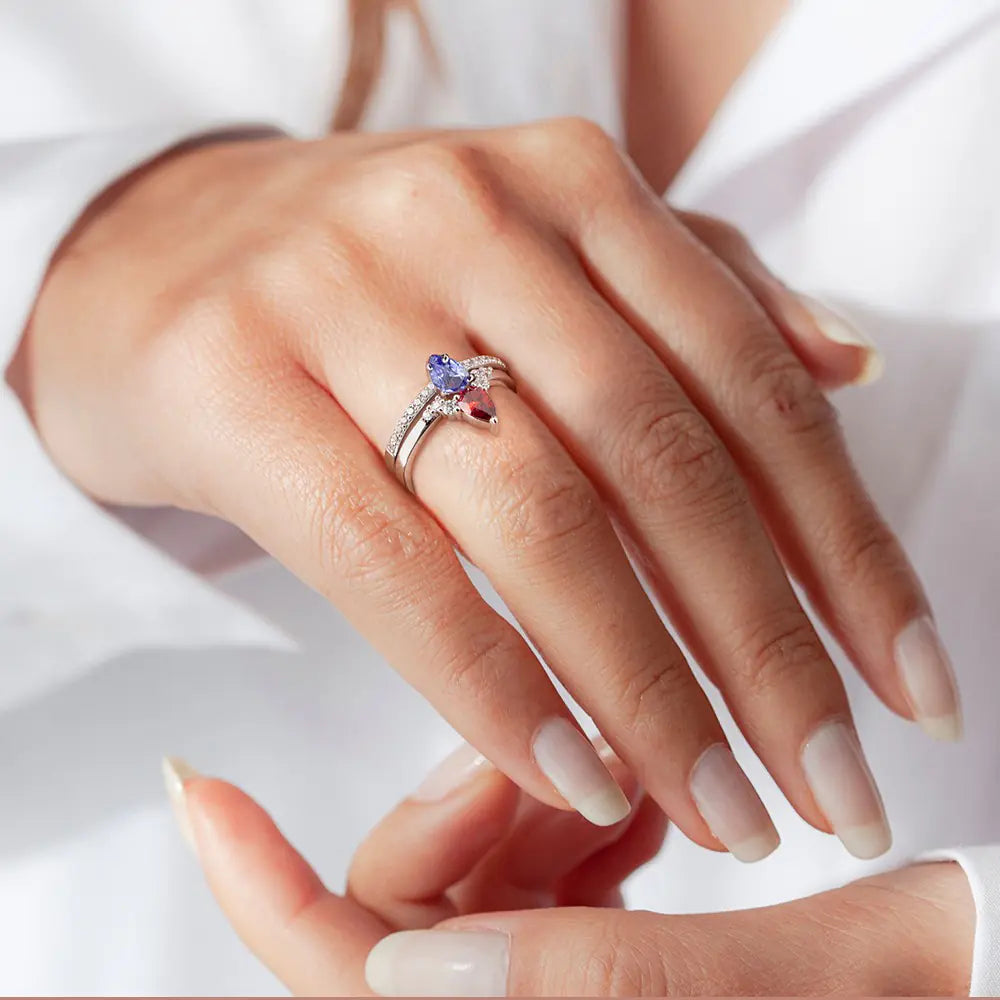 Woman wearing a personalized double birthstone ring with two pear-shaped stones on her hand.