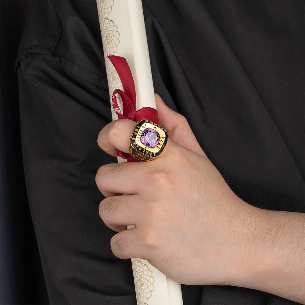 Gold custom men’s class ring with birthstone worn on hand, engraved class year and school details
