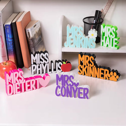 Multiple personalized 3D teacher name signs in different colors and icon designs displayed together

