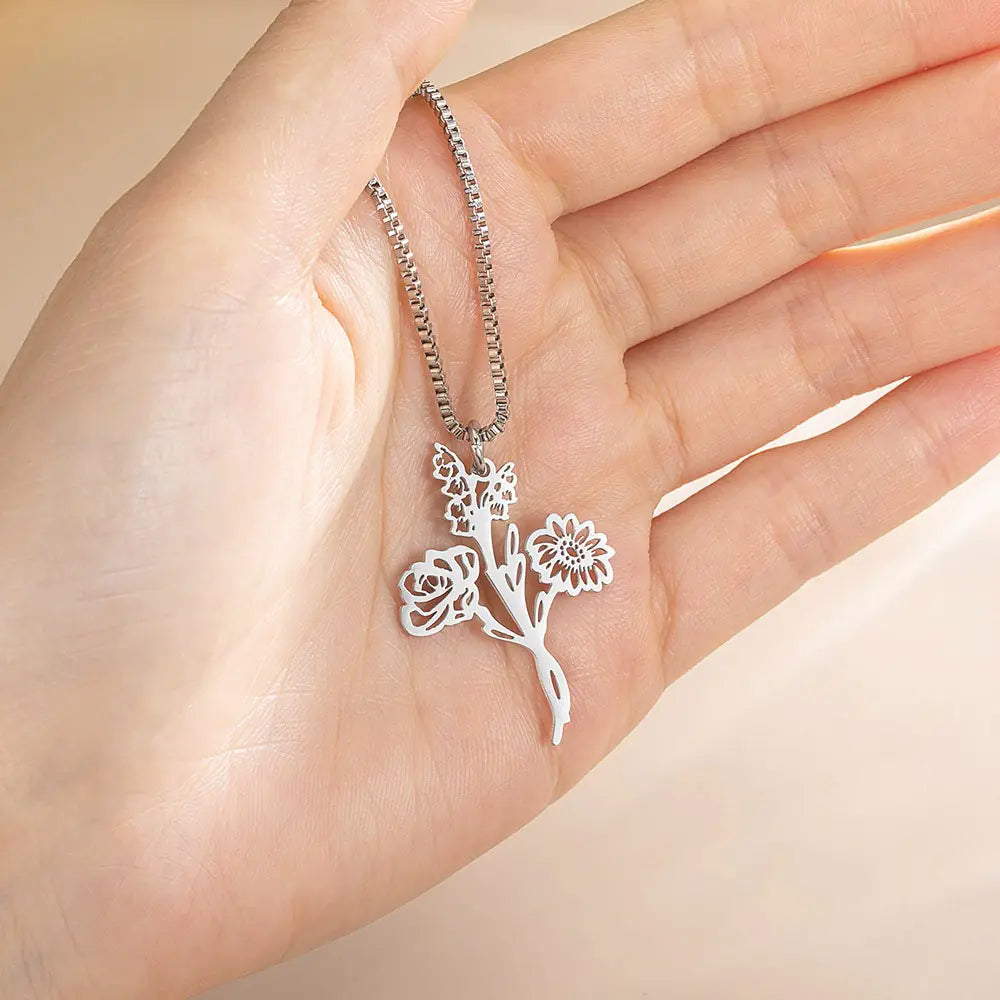 Silver birth flower bouquet necklace held in hand, personalized with multiple birth flowers for family members.