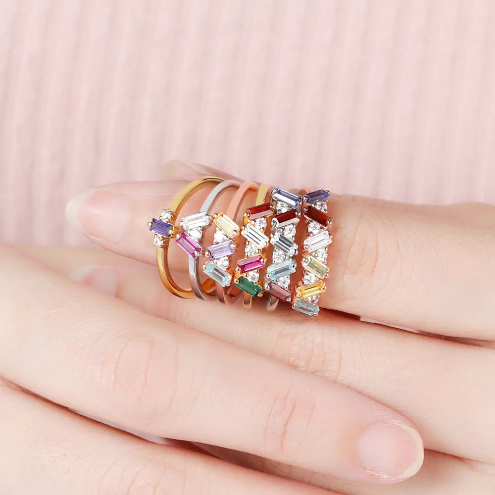Stacked custom baguette birthstone rings worn on fingers, personalized with multiple colorful birthstones