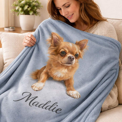 Woman holding a blue blanket with a dog illustration and name 'Maddie' on a couch.