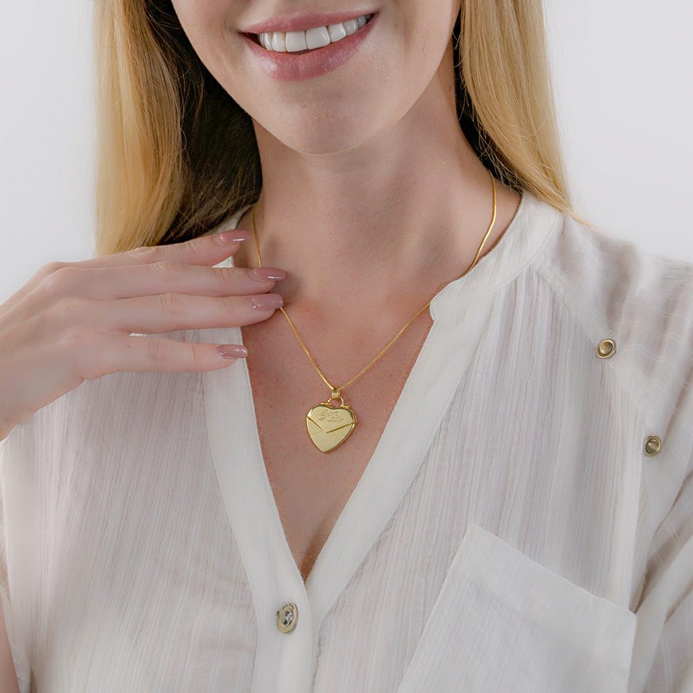 A women is wearing a gold custom secret message envelope heart locket necklace