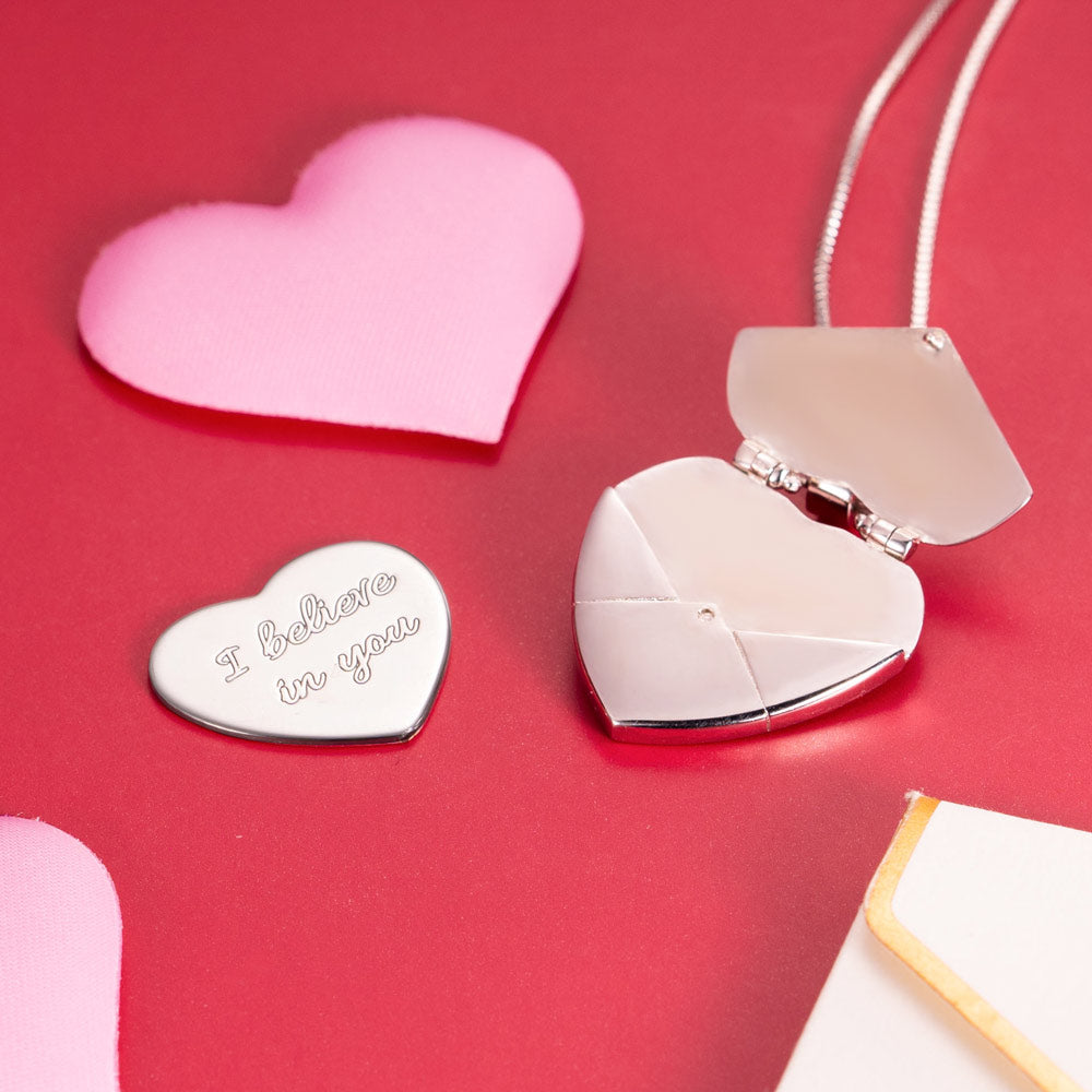 A open silver heart shaped locket necklace with a custom heart message read " I believe in you" 