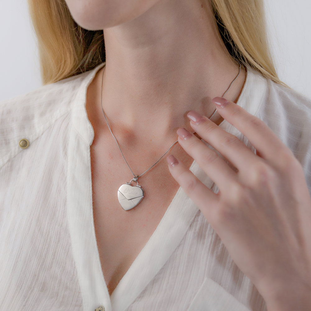 A women is wearing a silver custom secret message envelope heart locket necklace