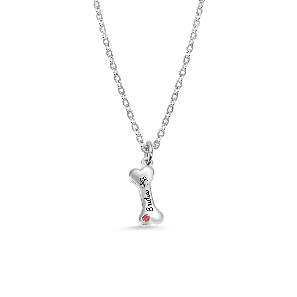A personalized silver dog bone pendant with birthstone and dog name engraved 