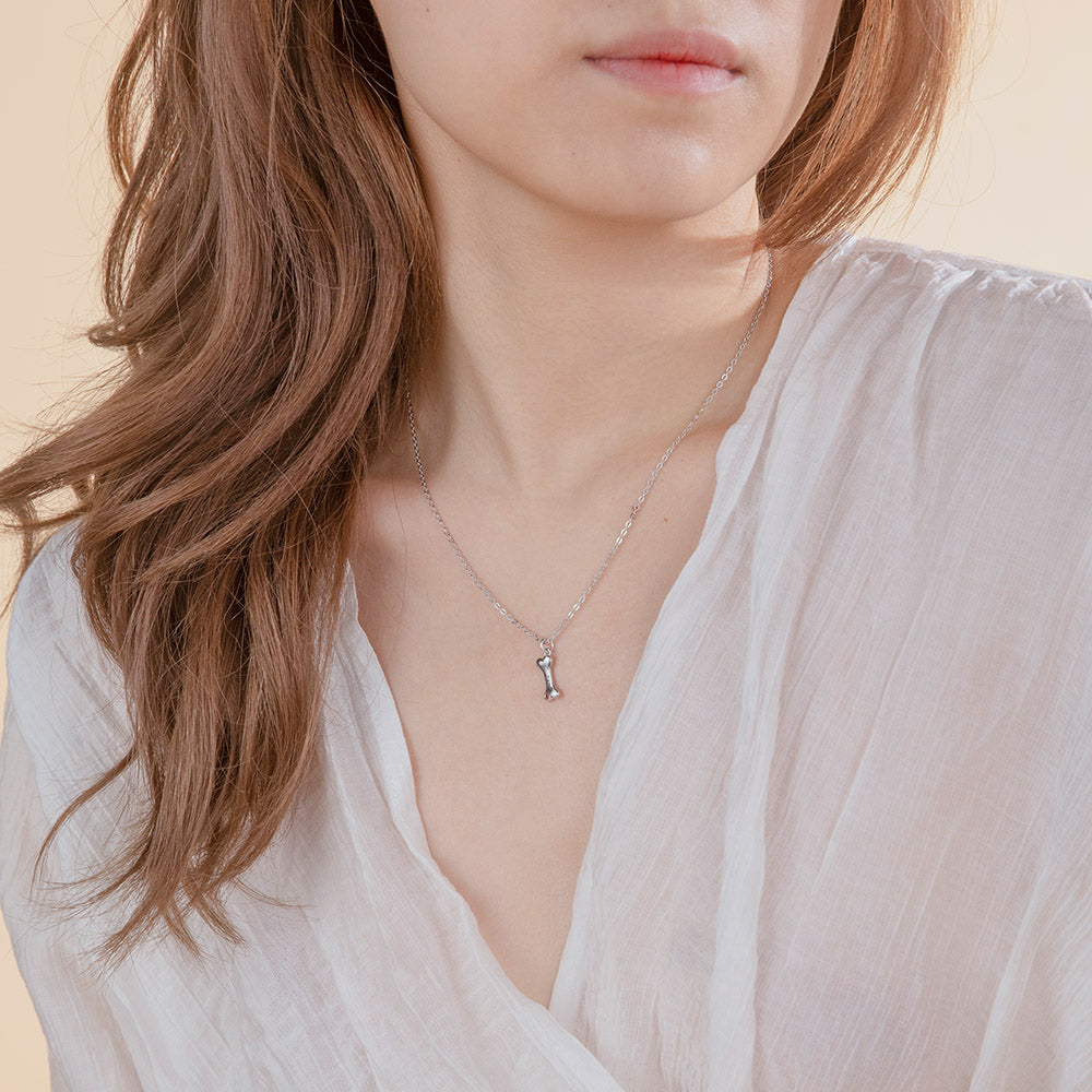 A women is wearing a custom dog bone pendant necklace with it's name engraved