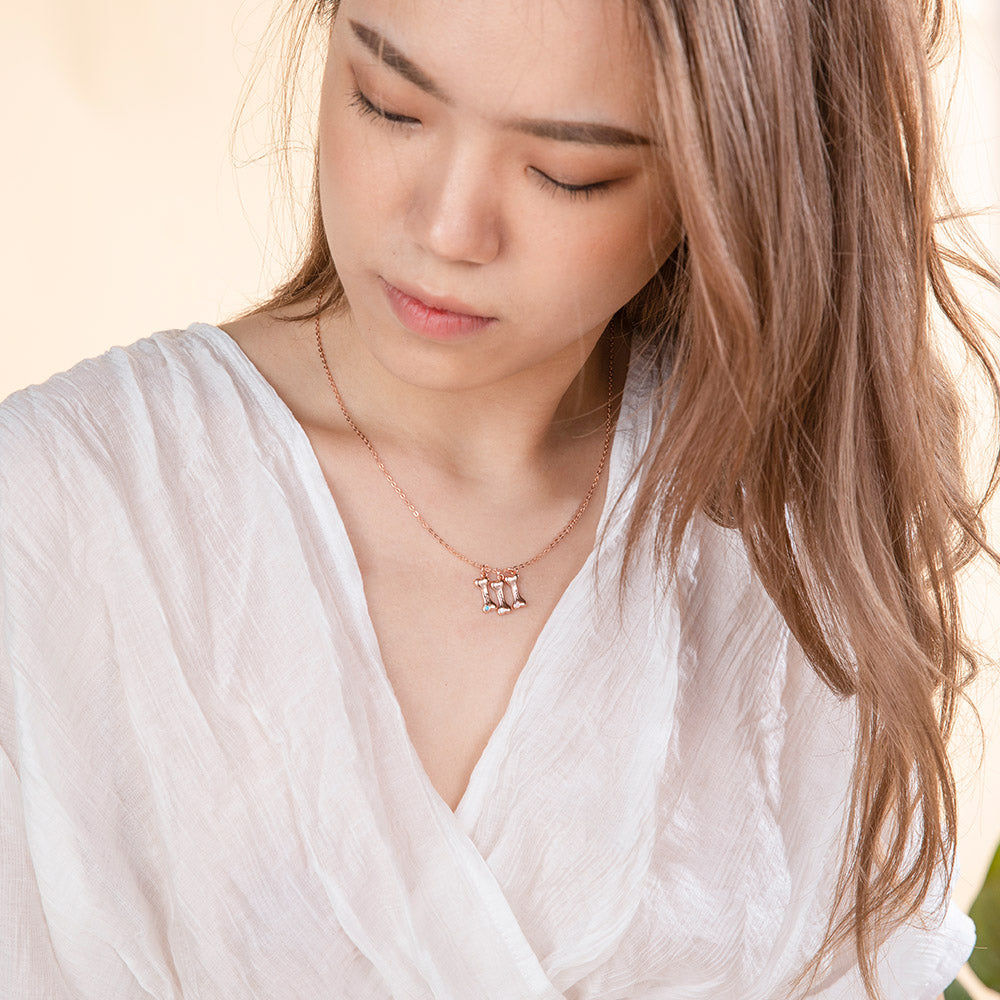 A women is wearing three custom dog bone pendant  necklace with their name engraved on each bone pendant
